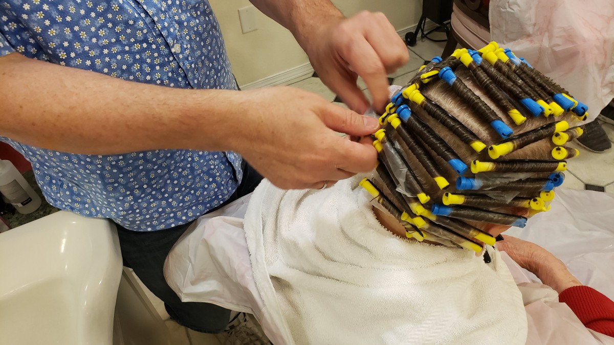 A person is setting hair with perm rods in a salon.