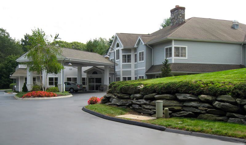 A large house with a landscaped driveway surrounded by greenery.