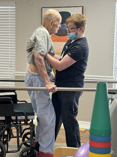 A healthcare professional assists a patient during a rehabilitation session.