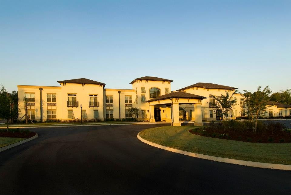 A large, modern residential building with well-maintained landscaping and a paved driveway during daytime.