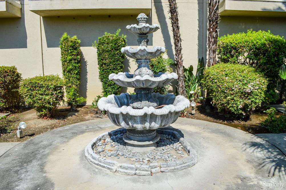 A decorative three-tiered stone fountain in a garden setting.