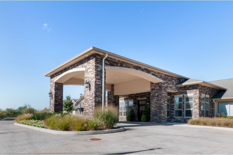 A well-maintained building with a stone facade and a covered entrance, surrounded by landscaping.