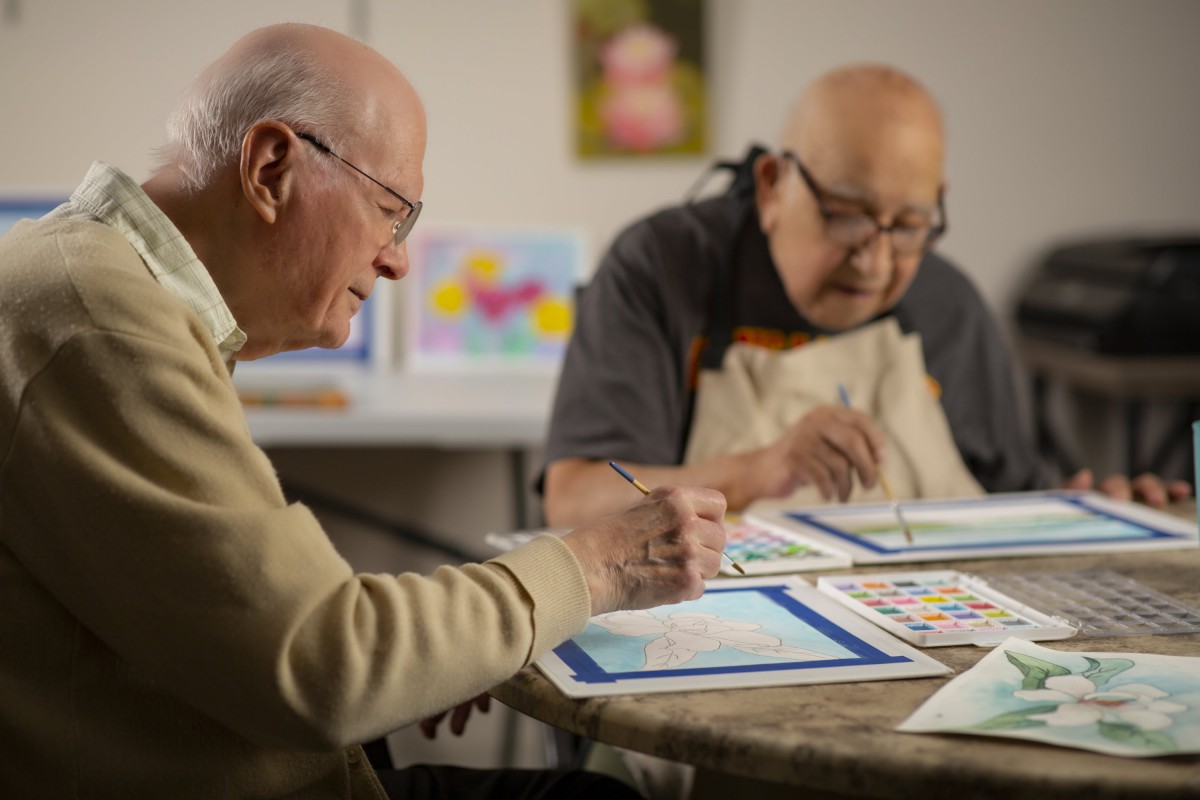 Two seniors enjoying a painting session together.