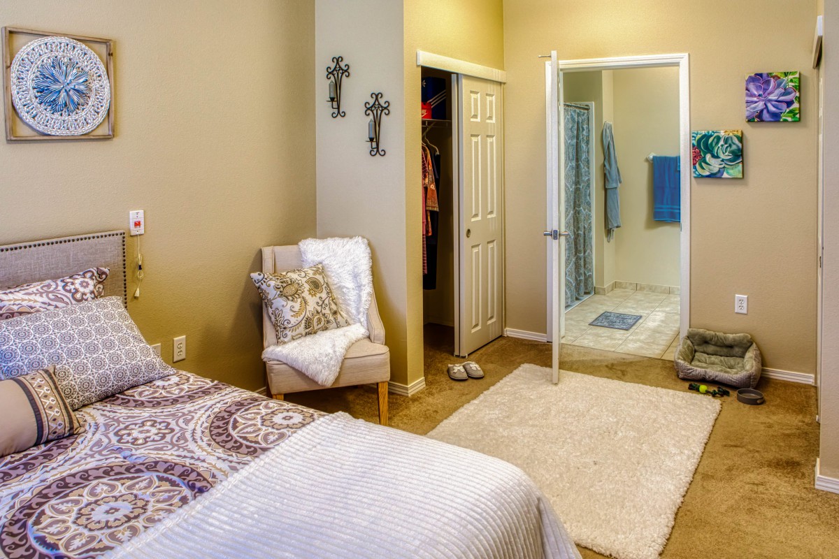 A cozy bedroom with a chair, closet, and an adjoining shower area.