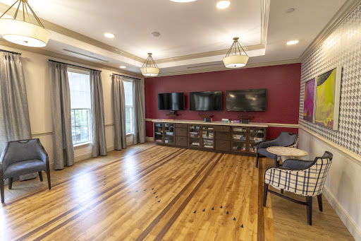 A stylish living room featuring hardwood flooring, modern furnishings, and flat-screen televisions.