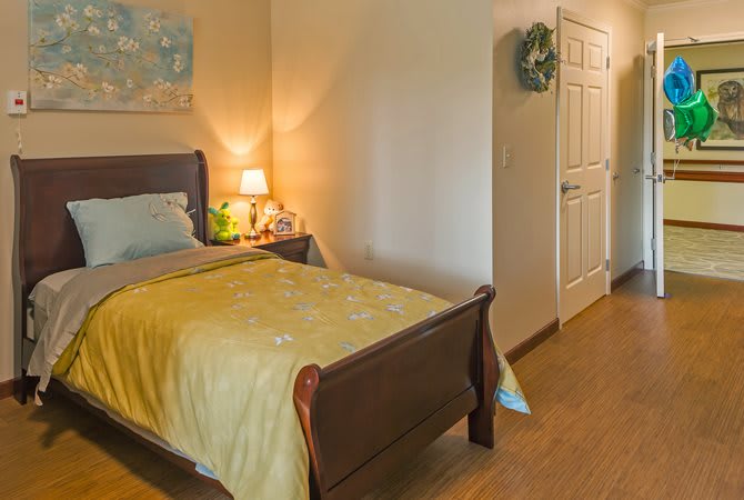 A cozy bedroom with a wooden bed, a bedside lamp, and simple decor.