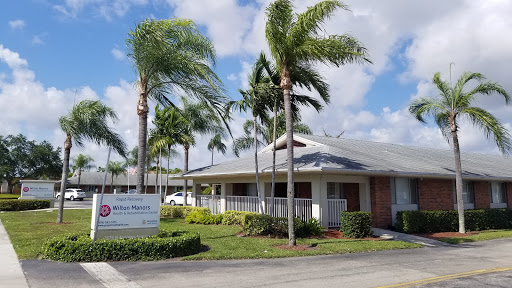 A charming residential building surrounded by palm trees under a partly cloudy sky.