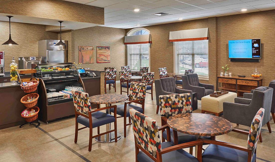 A cozy cafe interior with colorful chairs and tables, featuring large windows and a welcoming atmosphere.