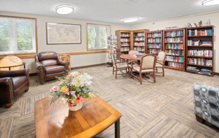 A cozy library with bookshelves, a reading table, and comfortable seating.