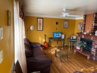 A cozy living room featuring a sofa, guitar, and television, with vibrant yellow walls and hardwood flooring.