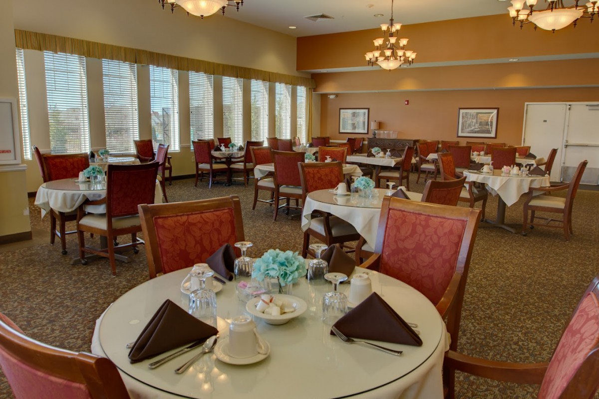 Elegantly set dining tables in a restaurant with large windows and warm lighting.