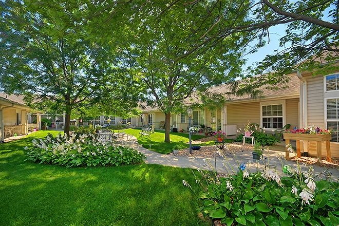 A serene garden setting with a lush lawn, mature trees, and a charming patio.