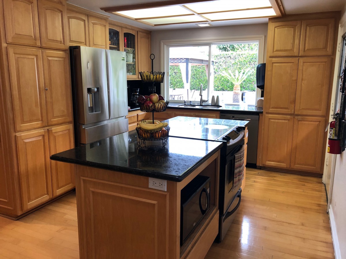 A modern kitchen featuring a large island with granite countertops and stainless steel appliances.