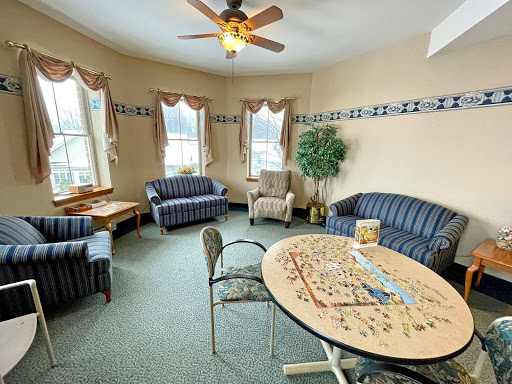 A cozy living area featuring comfortable sofas, a game table, and ample natural light.