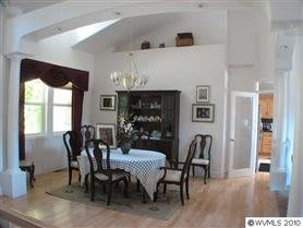 A cozy dining room with a table and chairs, elegant chandelier, and decorative furnishings.