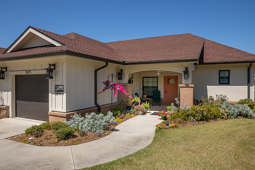 A charming single-story house with a welcoming front yard and colorful flowers.