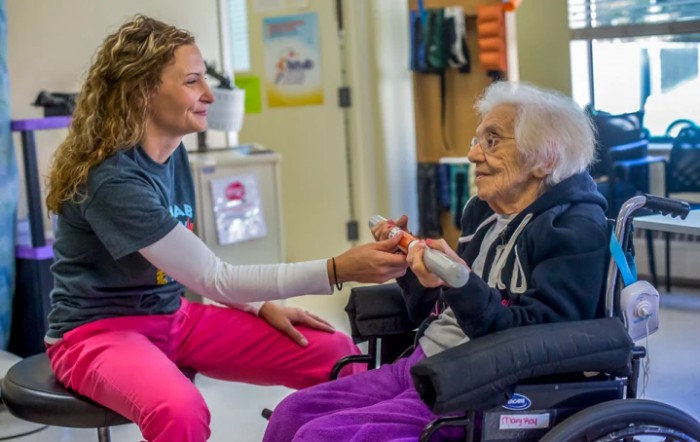 A caregiver interacting with an elderly person in a nursing home.