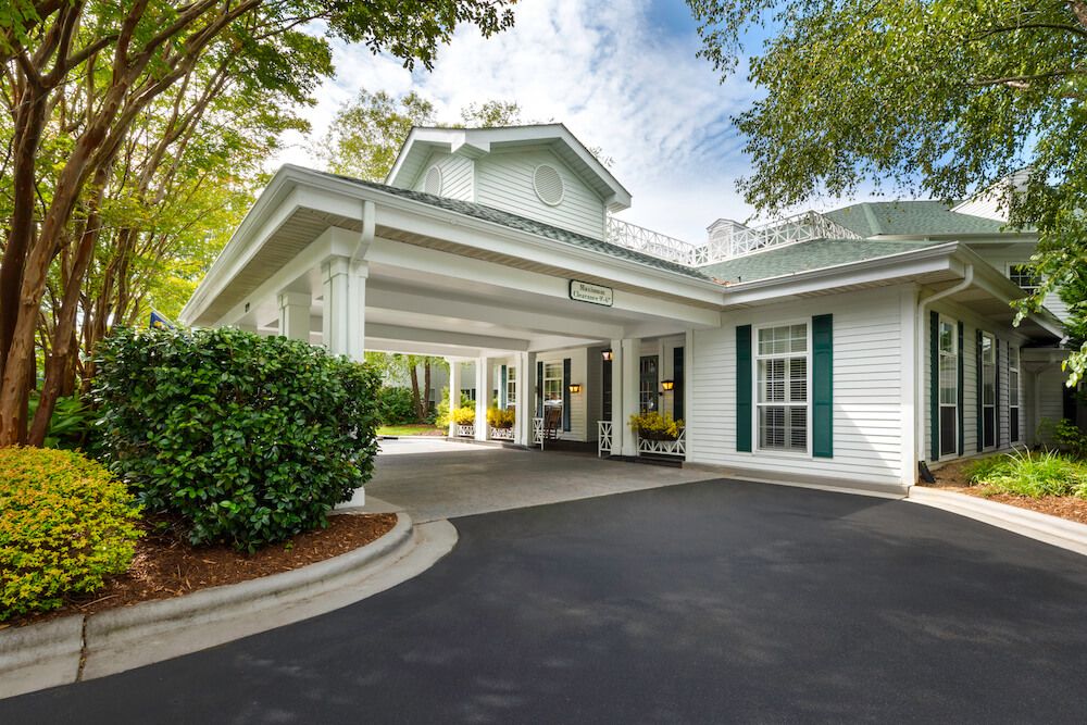 A welcoming building entrance with a driveway surrounded by trees.