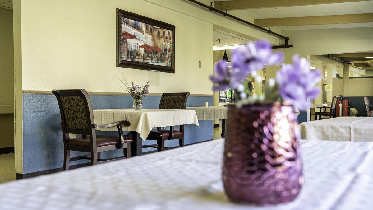 A cozy restaurant interior with neatly set tables and a vibrant floral centerpiece.