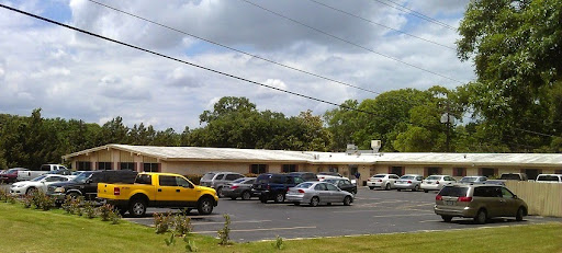 A view of a parking lot in front of a low-rise commercial building under a partly cloudy sky.