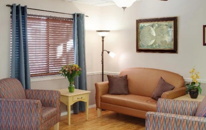 A cozy living room with a sofa, armchairs, and a vase of flowers on a side table.