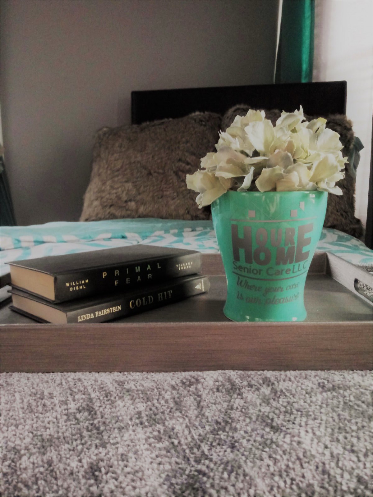 A cozy bedroom setup with a decorative tray holding books and a flower arrangement.