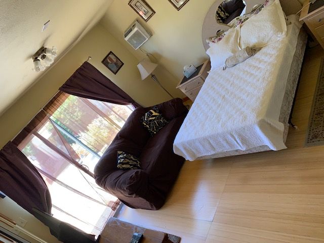 A cozy bedroom with a bed, couch, and large window with curtains.