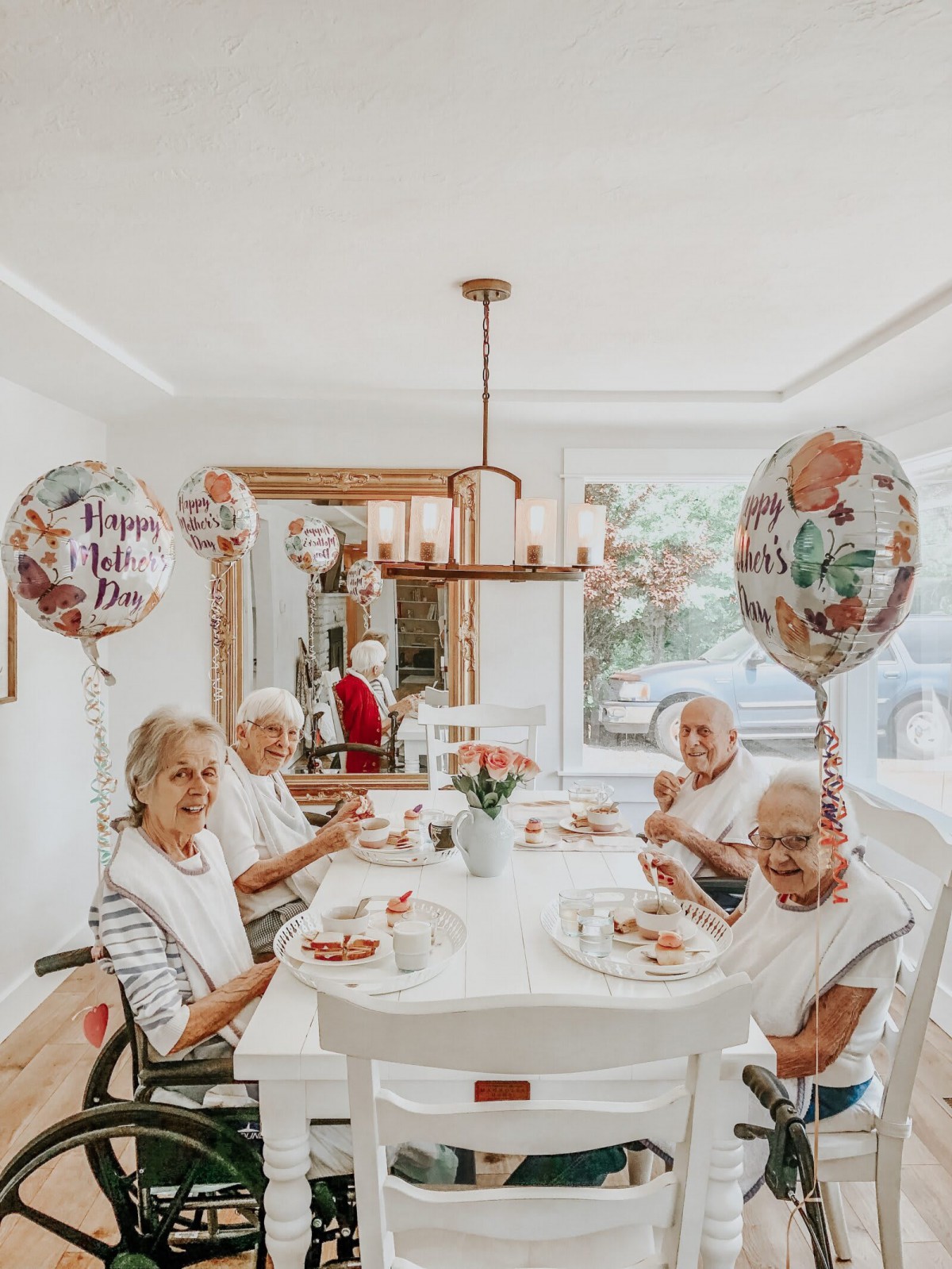 A group of elderly women enjoying a meal together, surrounded by festive balloons in a cozy dining room.