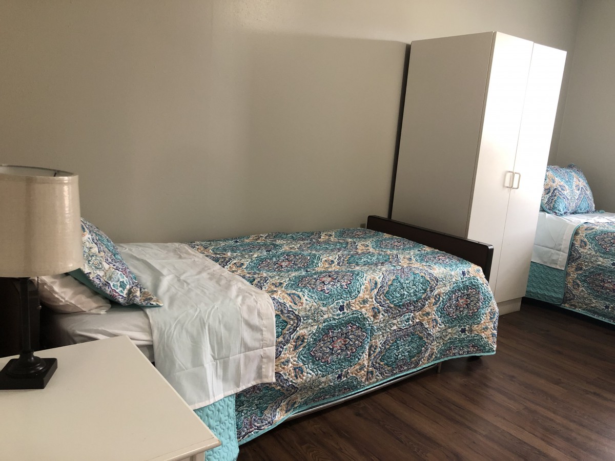 A neatly arranged bedroom with a colorful bedspread and a wardrobe.