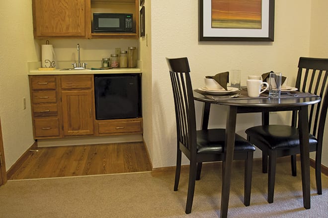 A cozy kitchen with a small dining area including a round table and chairs, adjacent to kitchen cabinets and appliances.