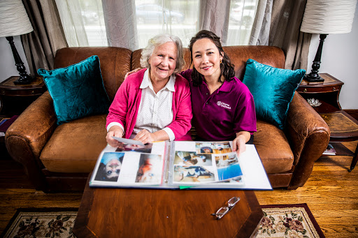 A joyful moment shared between a caregiver and an elderly woman as they look through a photo album together.