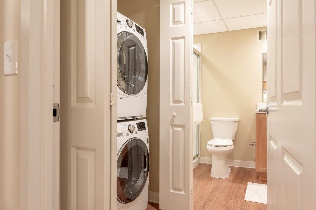 A compact laundry area with a stacked washer and dryer next to a bathroom.