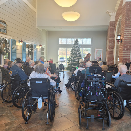 A community gathering of seniors in wheelchairs, enjoying a festive atmosphere with a decorated Christmas tree.