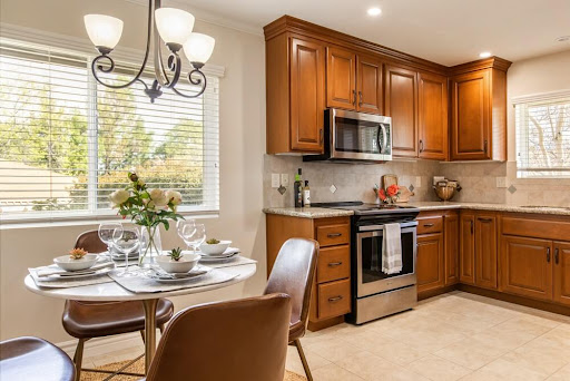 A beautifully designed kitchen featuring elegant wood cabinets and a cozy dining area, illuminated by natural light.