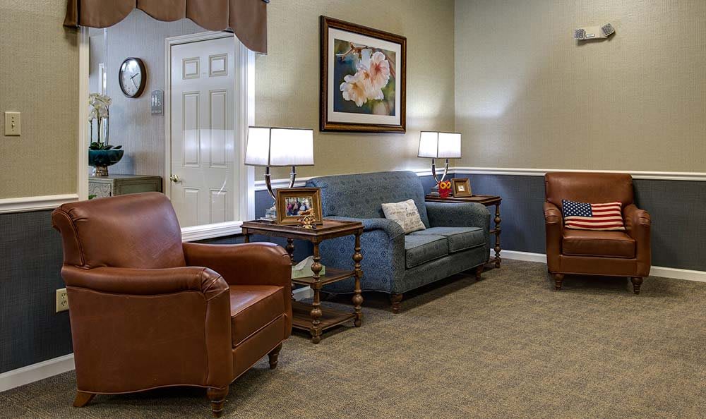 A cozy living room with a sofa, armchairs, and warm lighting.