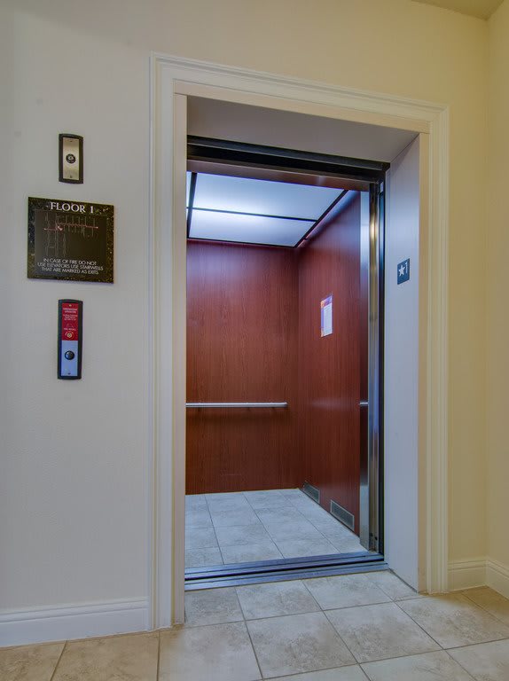 An open elevator with wooden interior walls and illuminated ceiling.