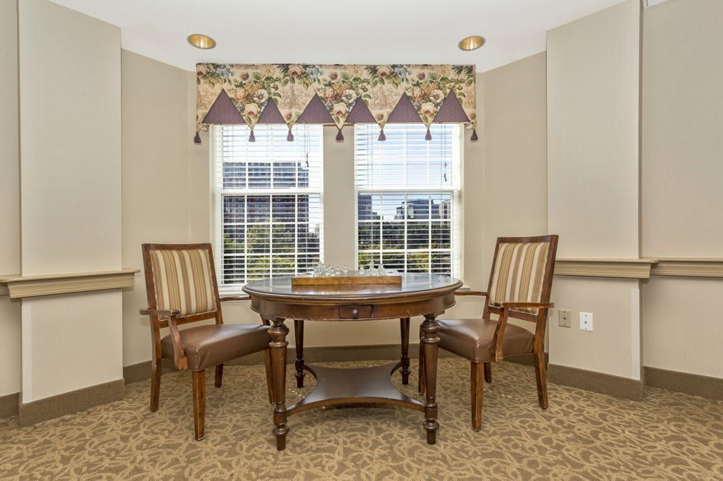 A cozy interior space with a round table and two chairs by the window.