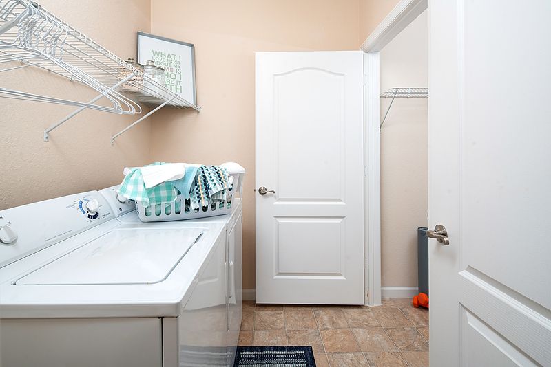 A tidy laundry room with a washing machine and dryer, featuring a laundry basket and clothes hangers.
