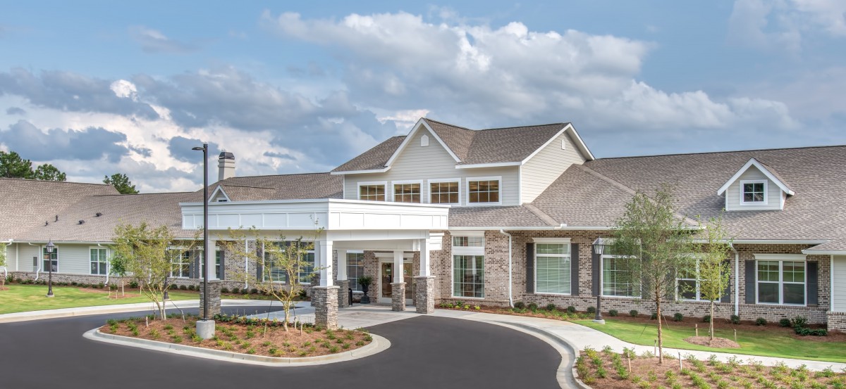 A modern residential building with a landscaped entrance and clear skies.
