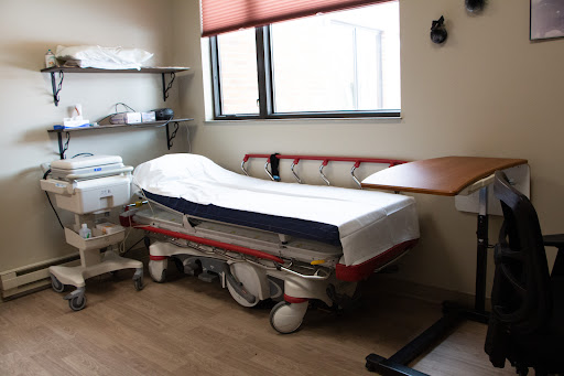 A view of a hospital room featuring an empty patient bed and medical equipment.