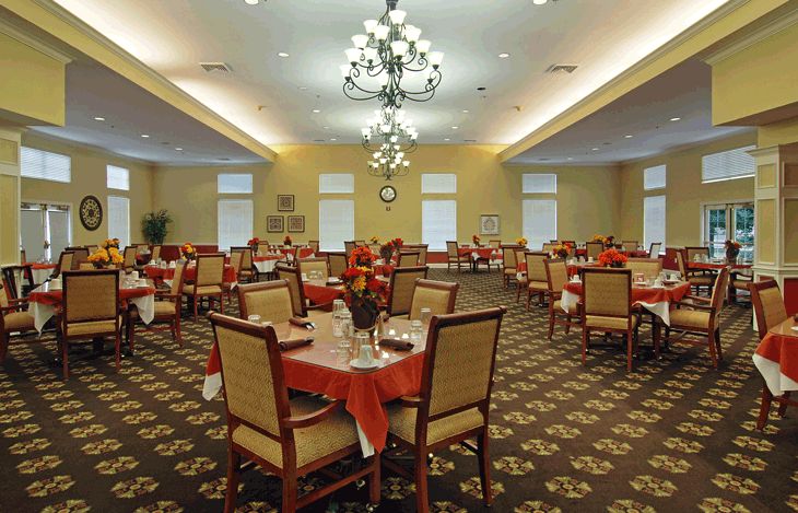 An elegant dining room with neatly arranged tables and chairs, adorned with chandeliers.