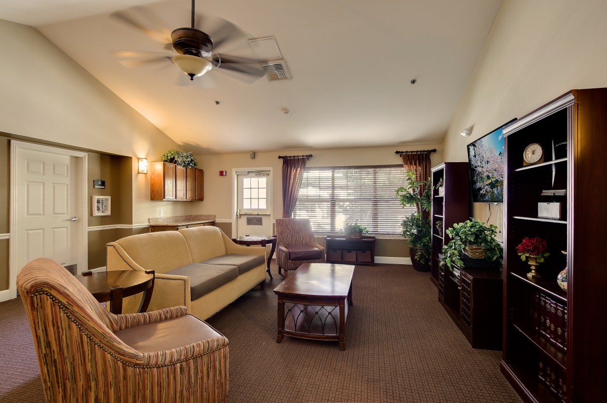 A cozy living room with a sofa, coffee table, ceiling fan, and decor.