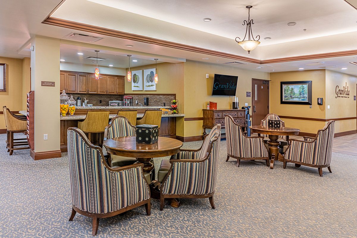A cozy dining area with round tables and striped chairs, featuring a modern TV and ambient lighting.