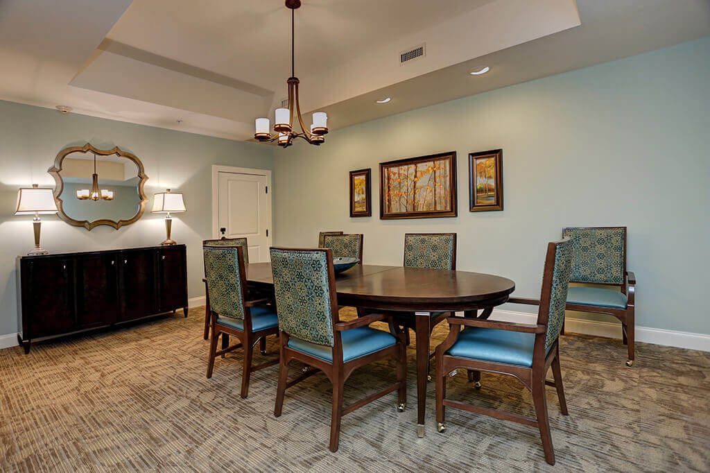 A well-appointed dining room with a round table and six chairs, complemented by elegant lighting and artwork.