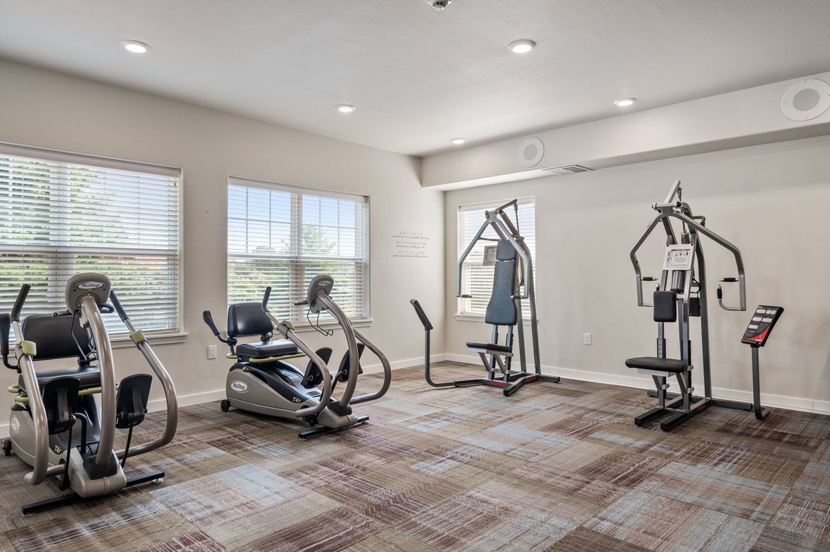 A gym room with various fitness equipment and exercise machines.