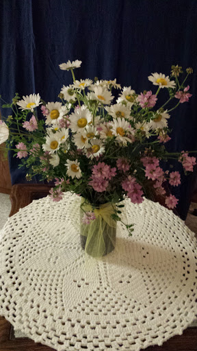 A vibrant bouquet of daisies and pink flowers arranged in a glass vase, adding a touch of beauty to the table.