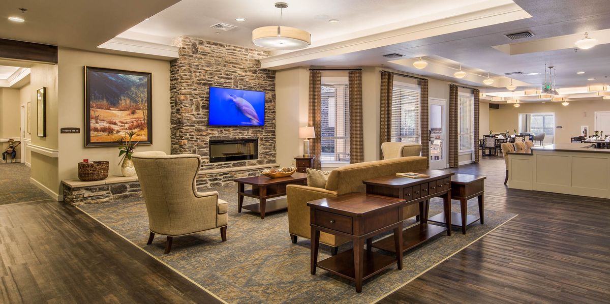 A cozy living room with a stone fireplace, comfortable seating, and a television mounted above the mantel.