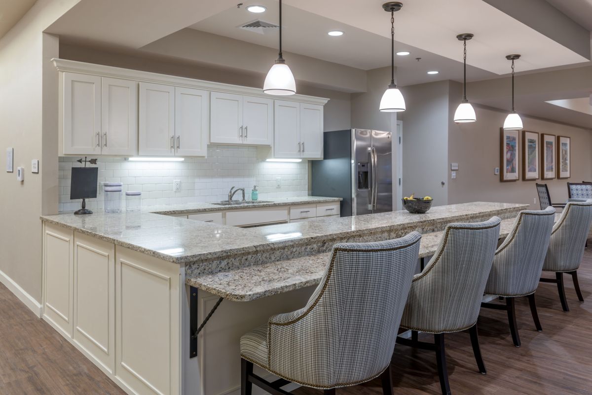 A modern kitchen featuring an island with granite countertops, white cabinets, and stylish pendant lighting.