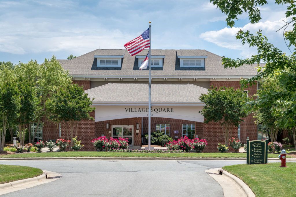 A brick building with an American flag in front, surrounded by trees and landscaping.