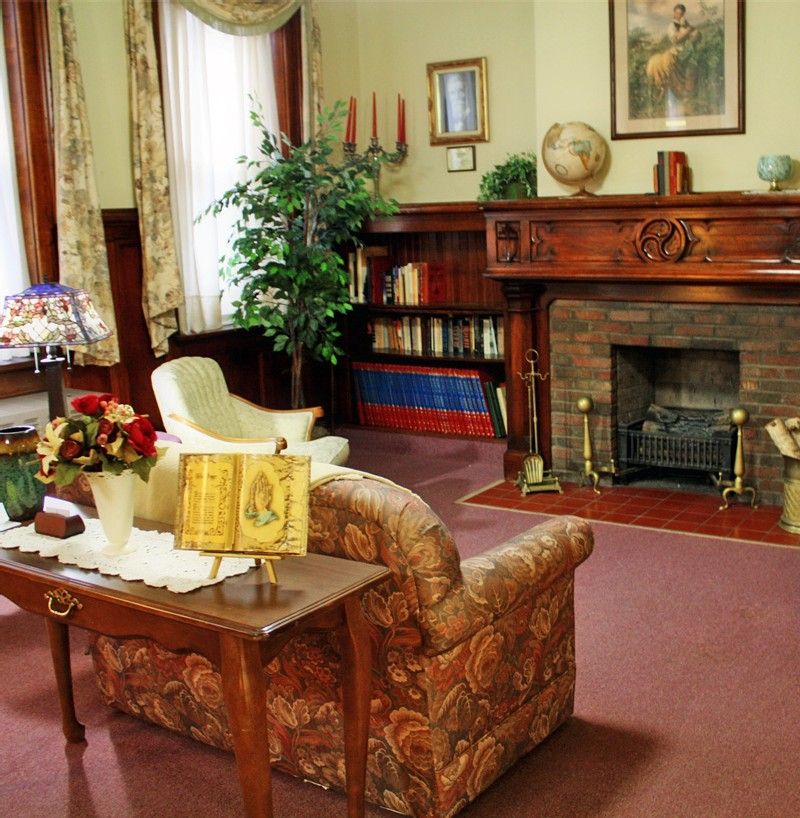 A cozy vintage living room with a fireplace, bookshelf, and classic furniture.